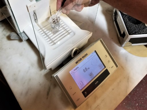 Precision laboratory scale with digital indicator being tested using certified calibration weights for accurate measurement